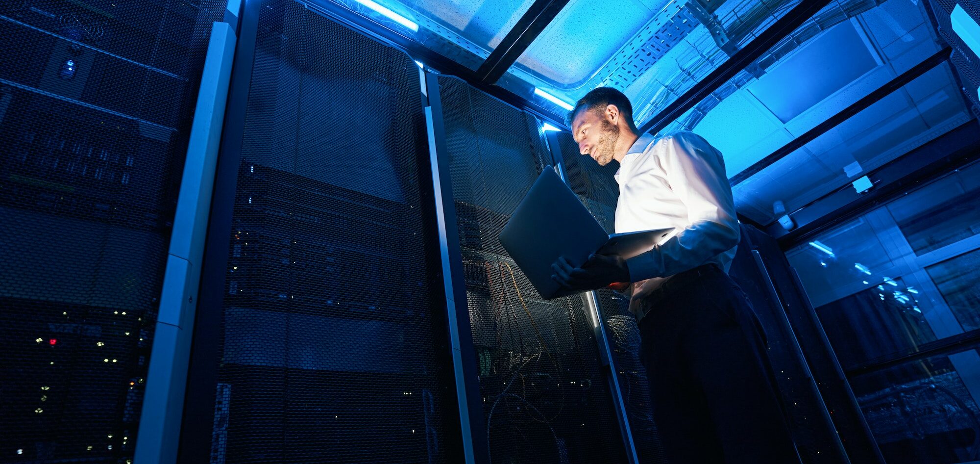 Network administrator using laptop while doing computer equipment checkup